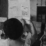 A young child adds her notes on a presentation board.