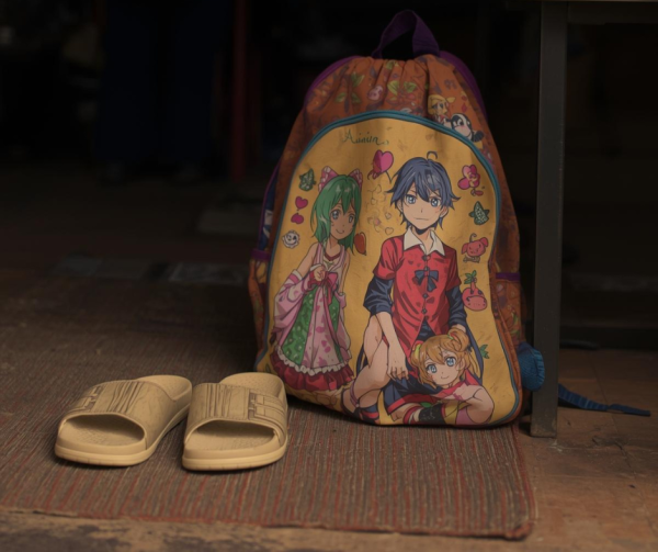 A child's backpack and sandals sit on a mat outside the shelter
