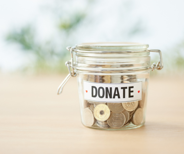a jar of coins on the counter attached is a piece of paper that says, "donate"