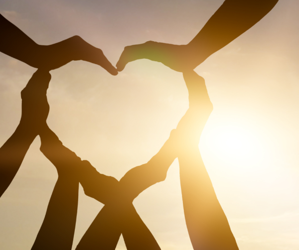 Hands forming a heart shape with sun pouring through.