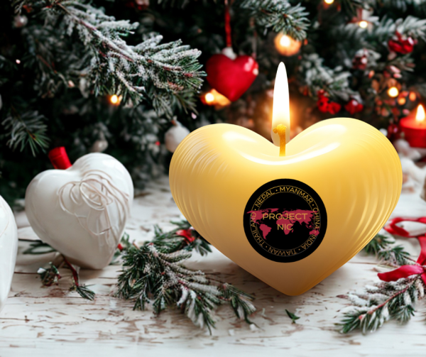 Christmas greenery with a warm glowing heart shaped candle bearing the Project Nic logo in front.