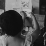 A young girl adds a note to a presentation board